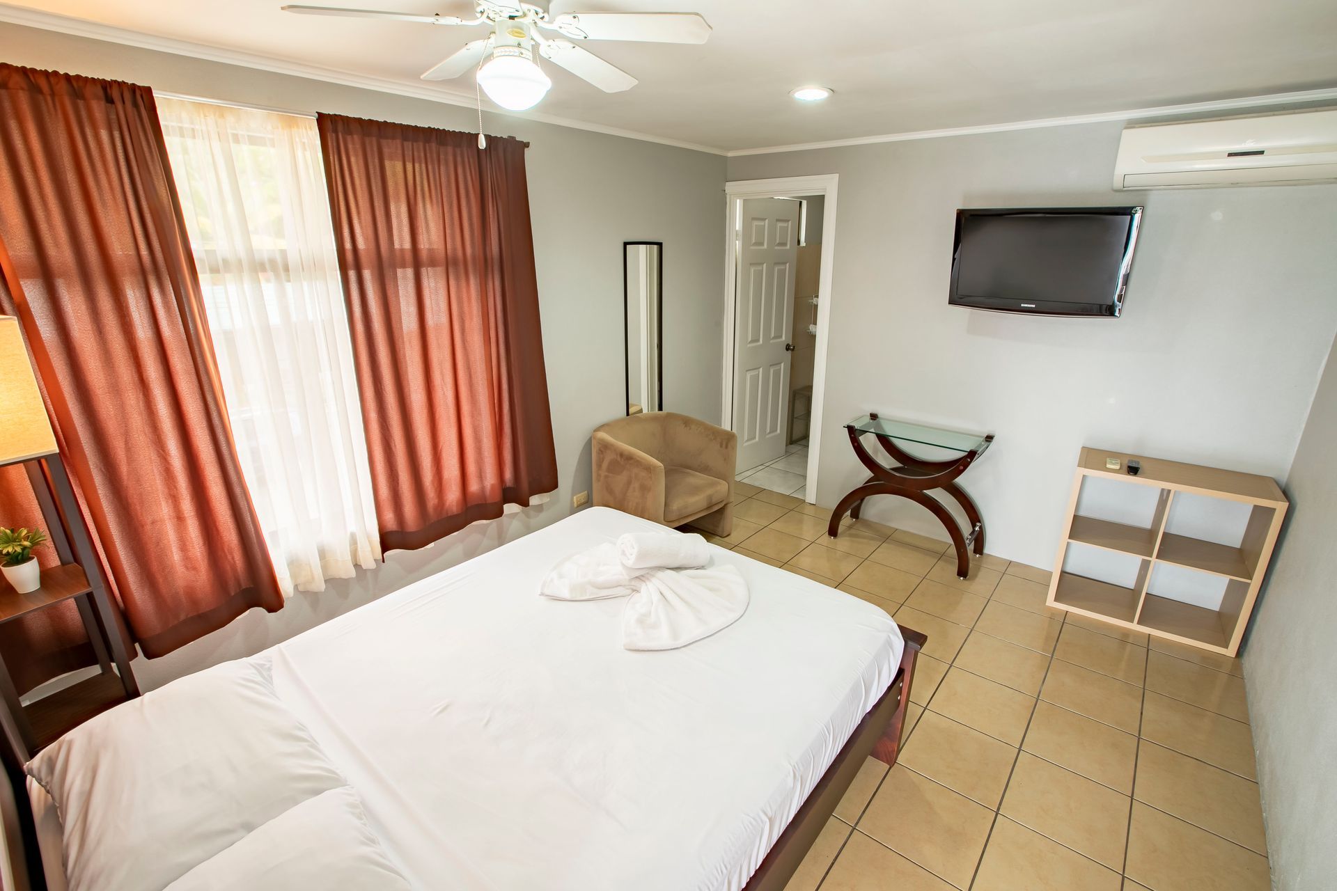 a hotel room with a king size bed , chair , television and ceiling fan .