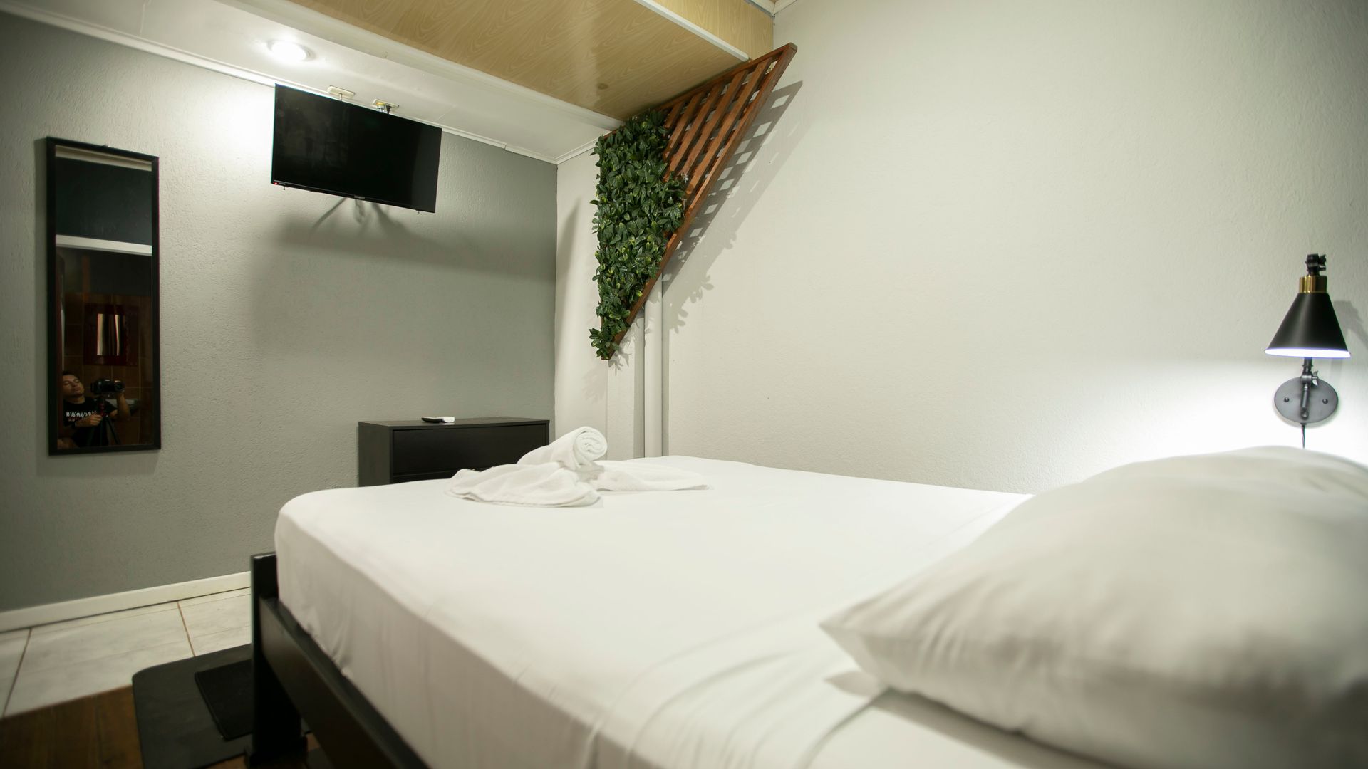 a bedroom with a bed , television , mirror and lamp .