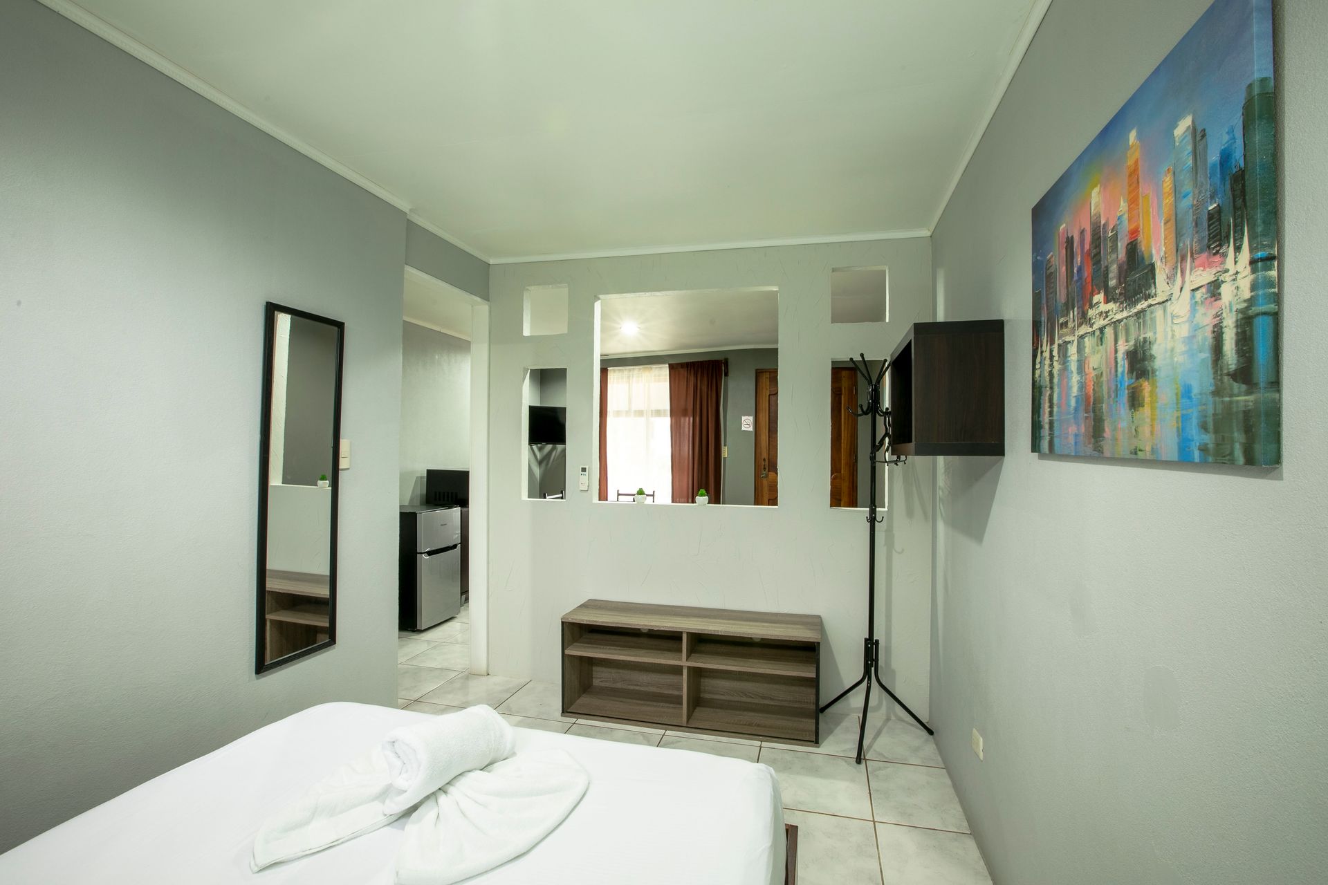 there is a painting on the wall above the bed in the room .