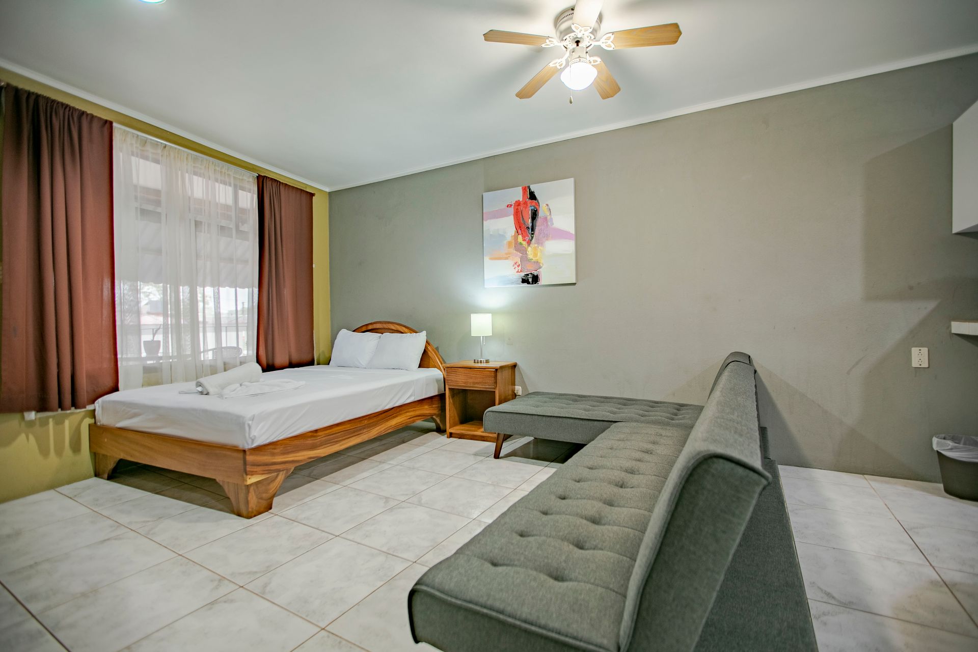 a hotel room with a bed , couch , and ceiling fan .