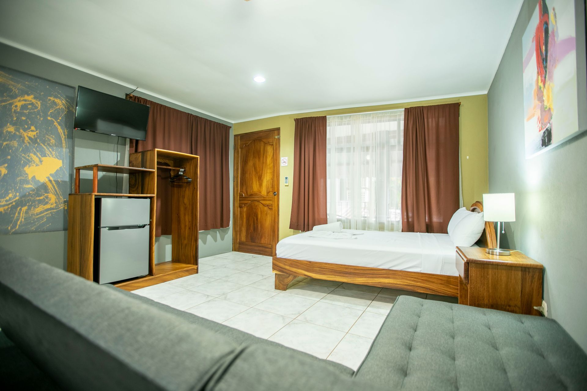 a hotel room with a bed , couch , refrigerator and television .