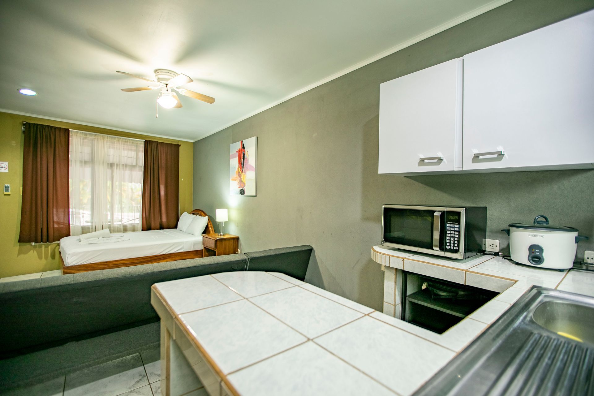 a kitchen in a hotel room with a microwave and a sink