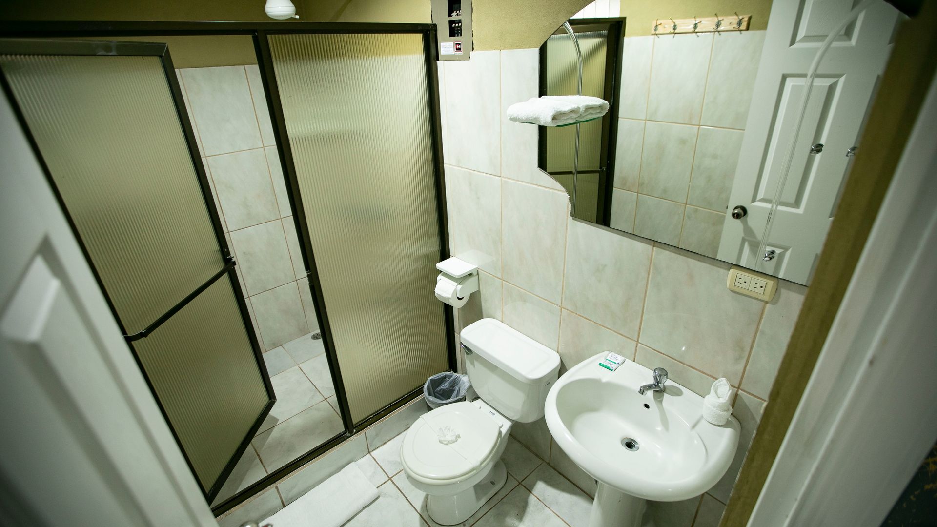 a bathroom with a toilet , sink , shower and mirror