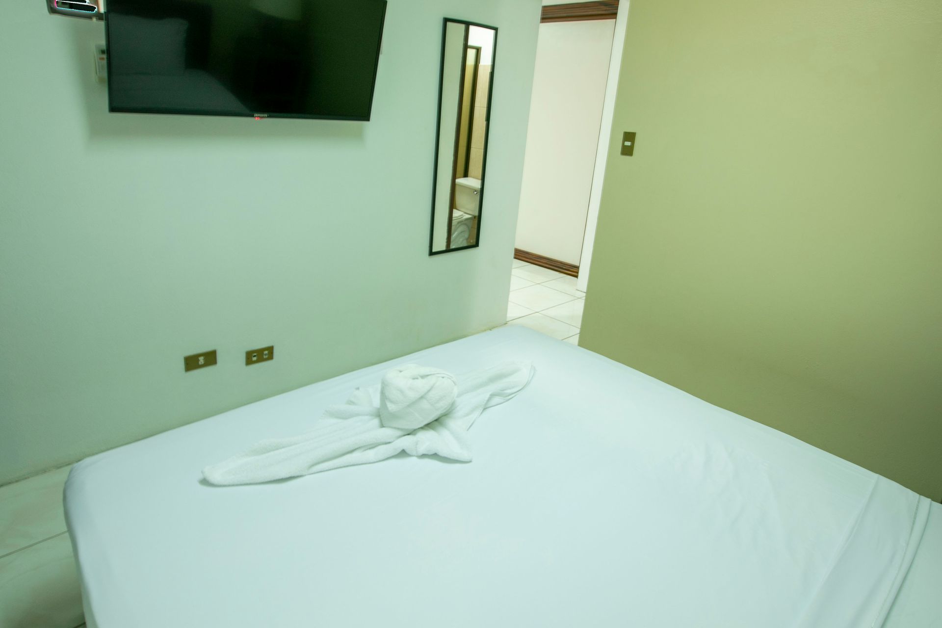 a hotel room with a bed , television and mirror .