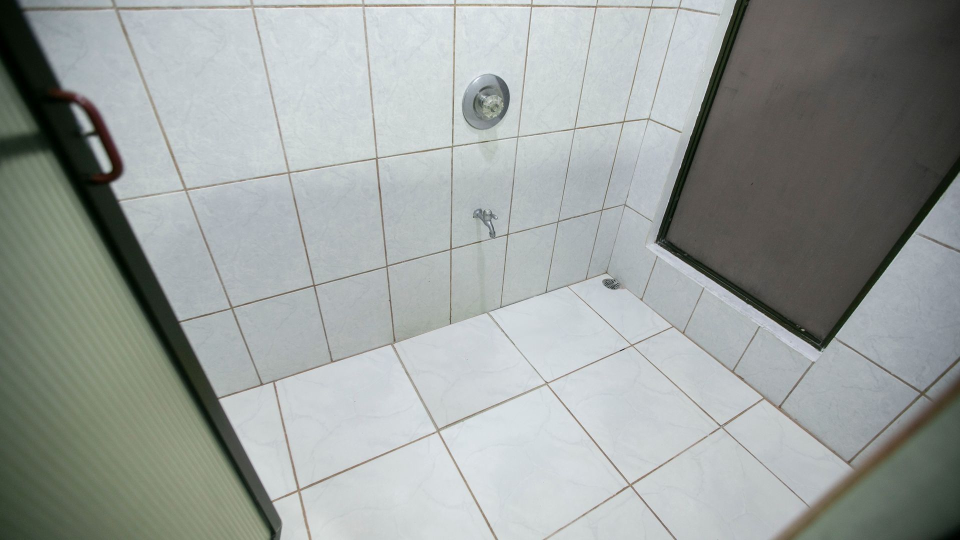a bathroom with white tiles and a shower stall