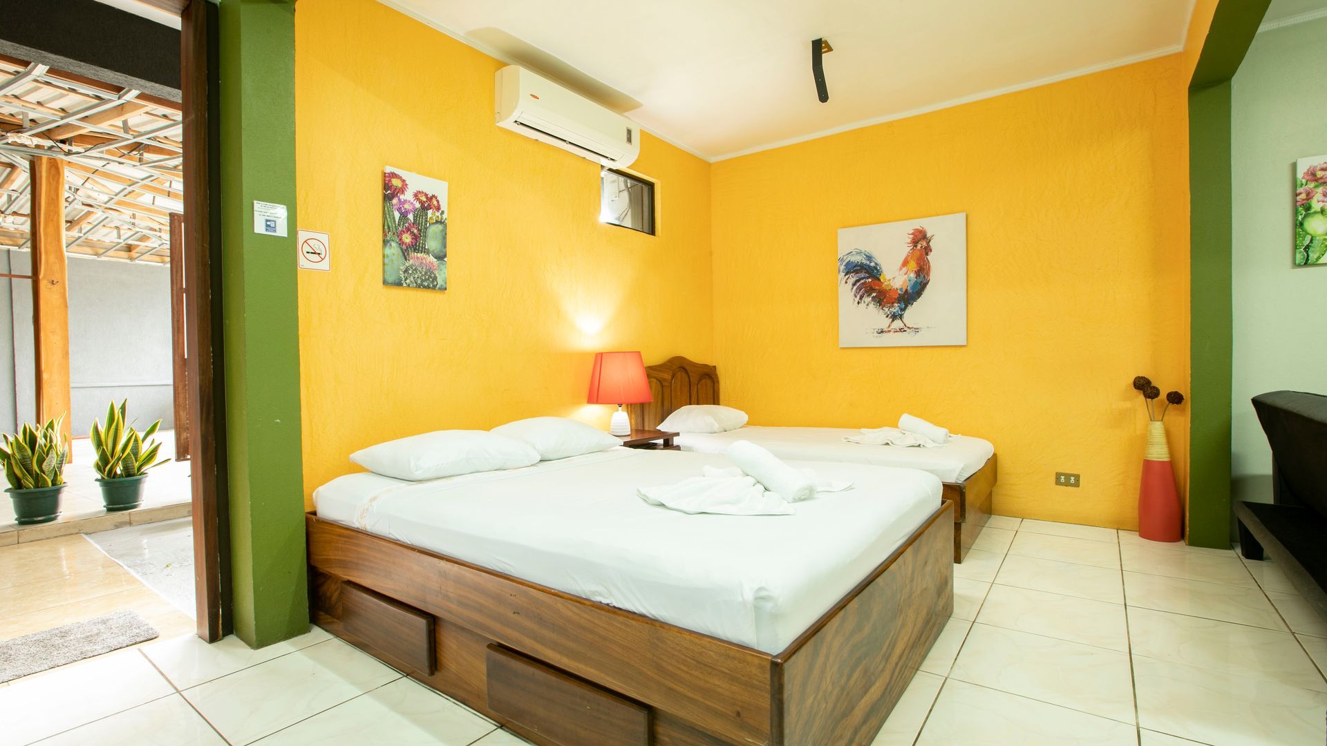 a hotel room with two beds and a painting of a rooster on the wall .