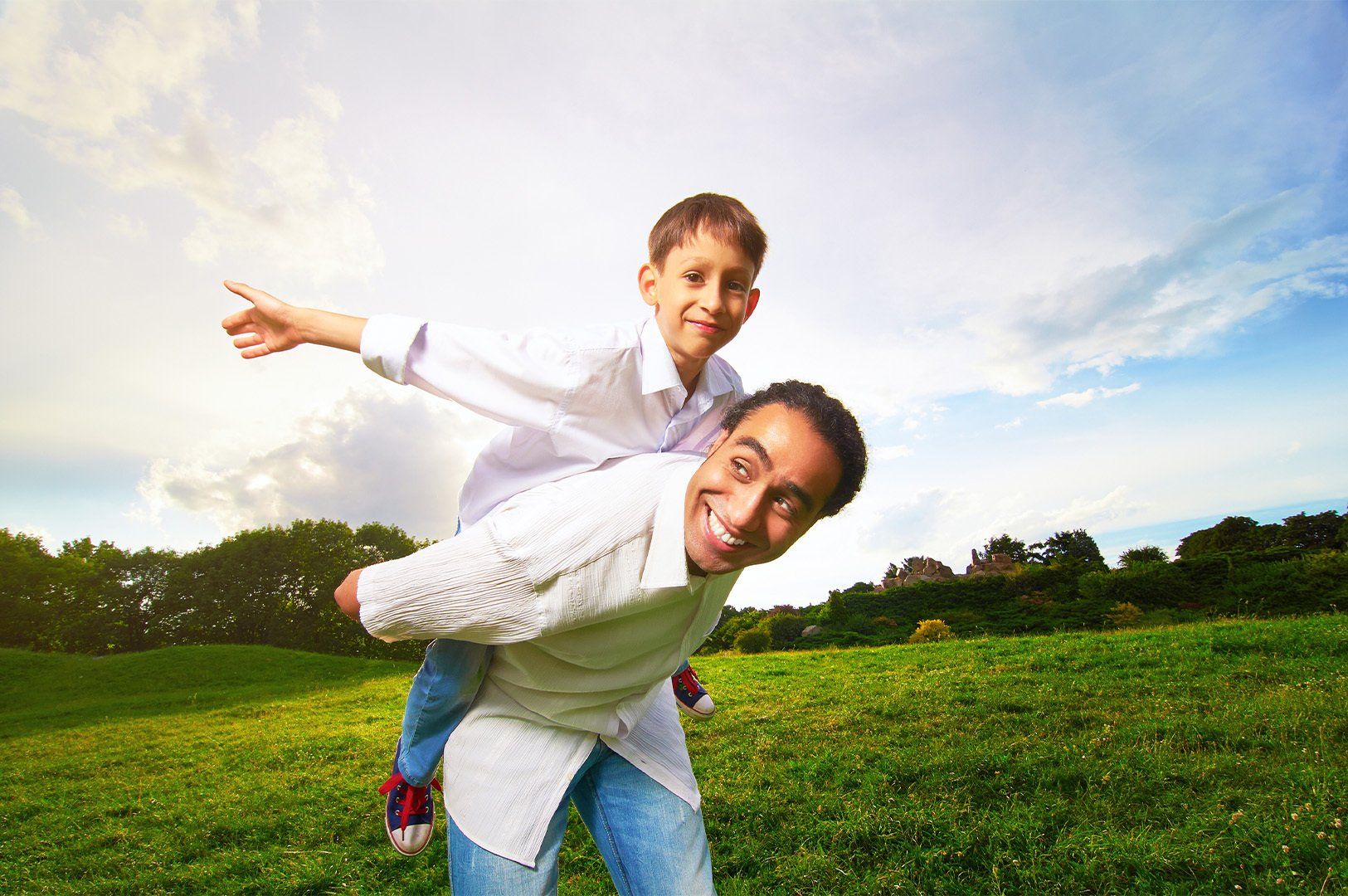 Man giving young boy piggyback ride outdoors smiling