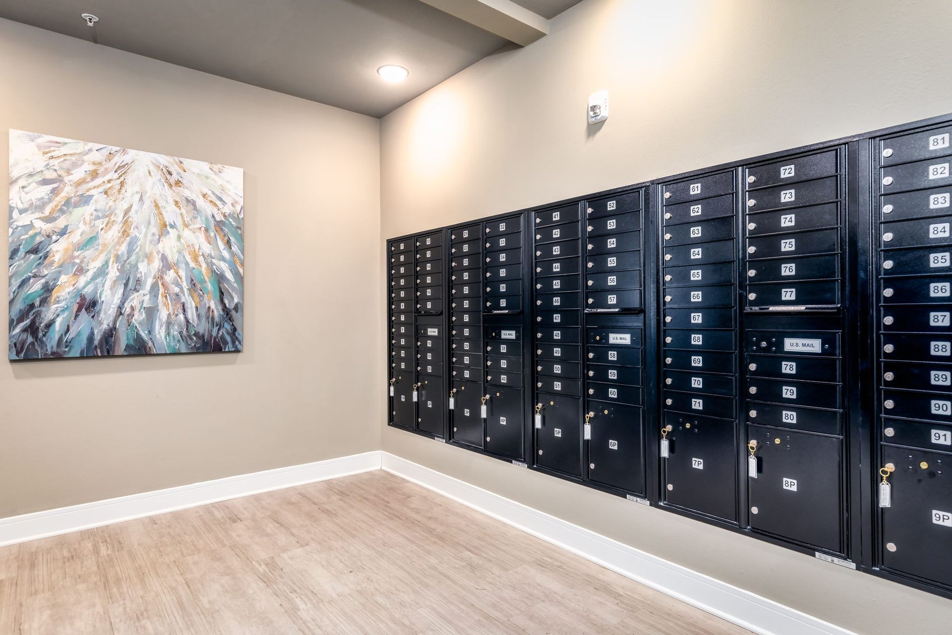 A room with a lot of mailboxes on the wall and a painting on the wall.