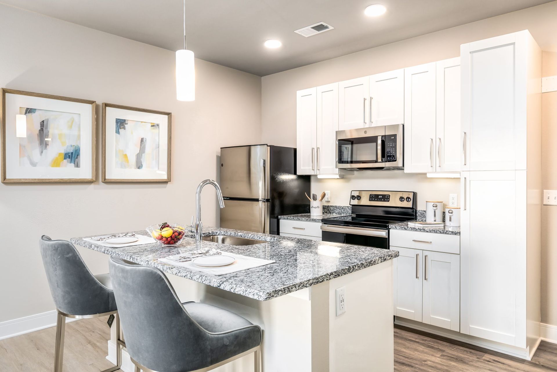 A kitchen with white cabinets , granite counter tops , stainless steel appliances and a refrigerator.