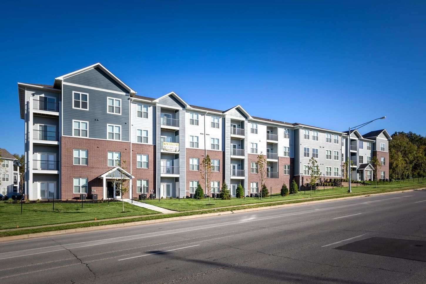 A large apartment building is sitting on the side of a road.
