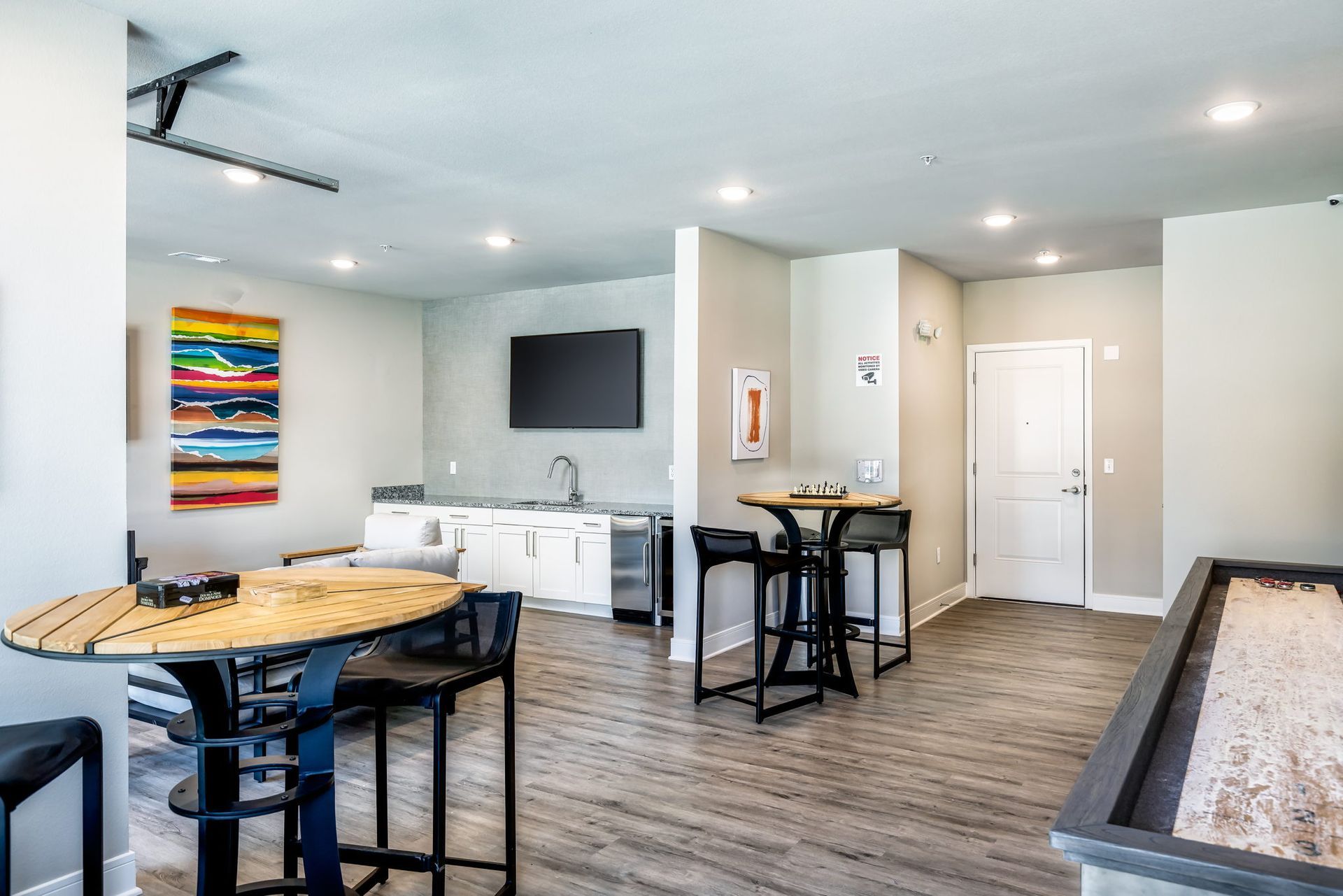 A living room with tables and chairs and a shuffleboard table.