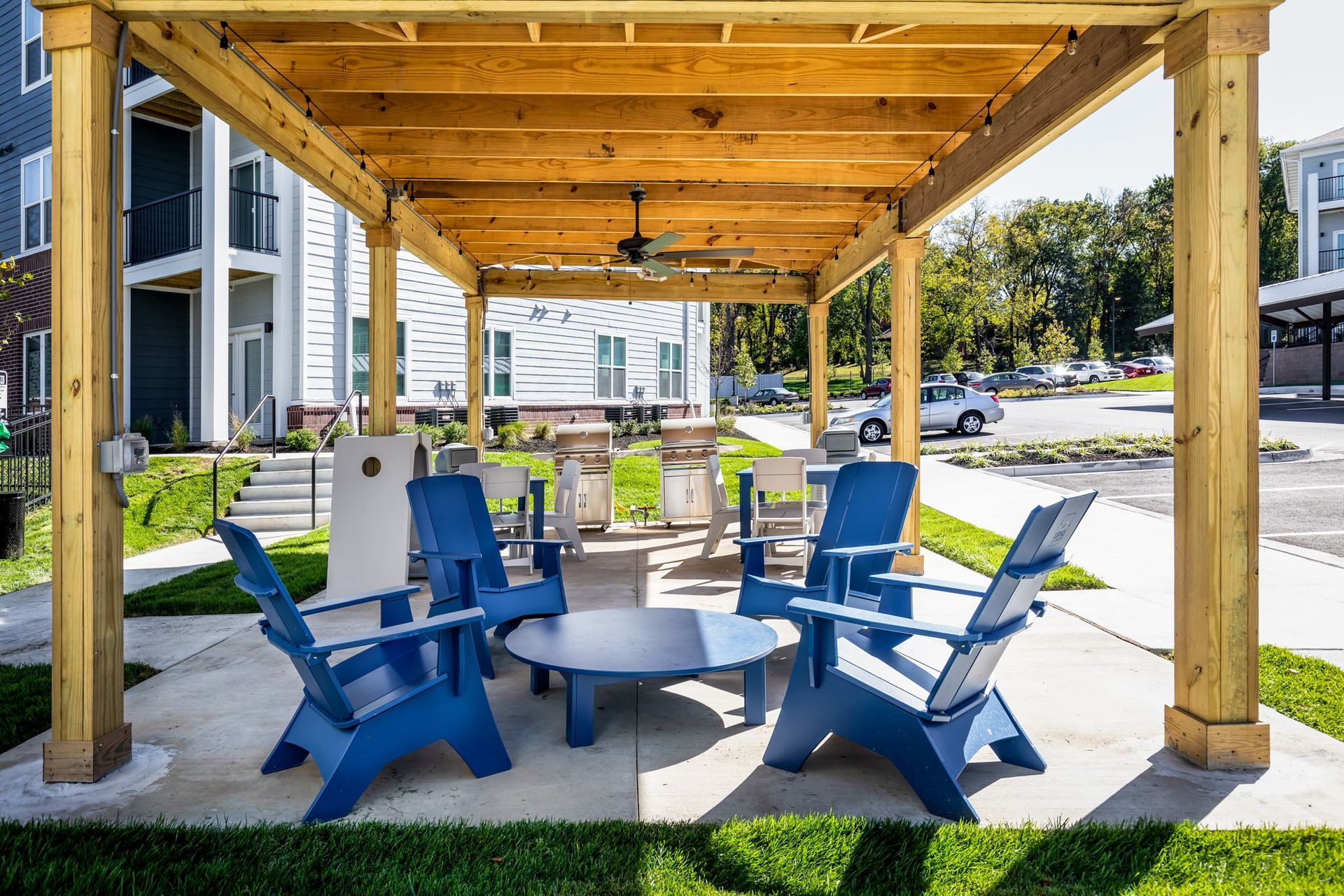 A group of blue chairs are sitting under a wooden pergola.