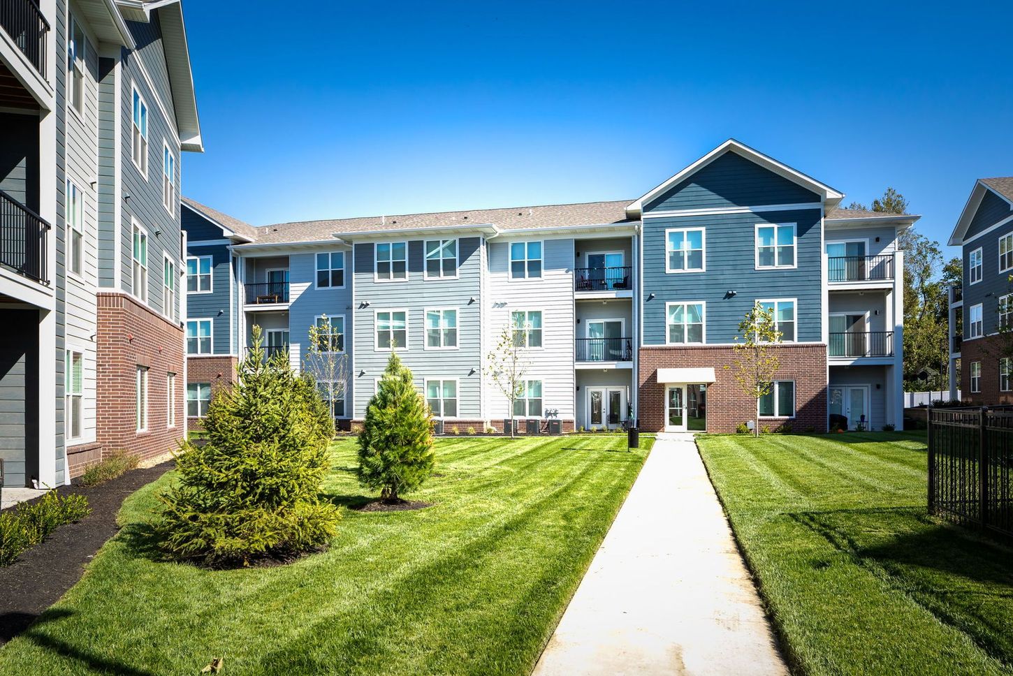 A large apartment building with a lush green lawn in front of it.