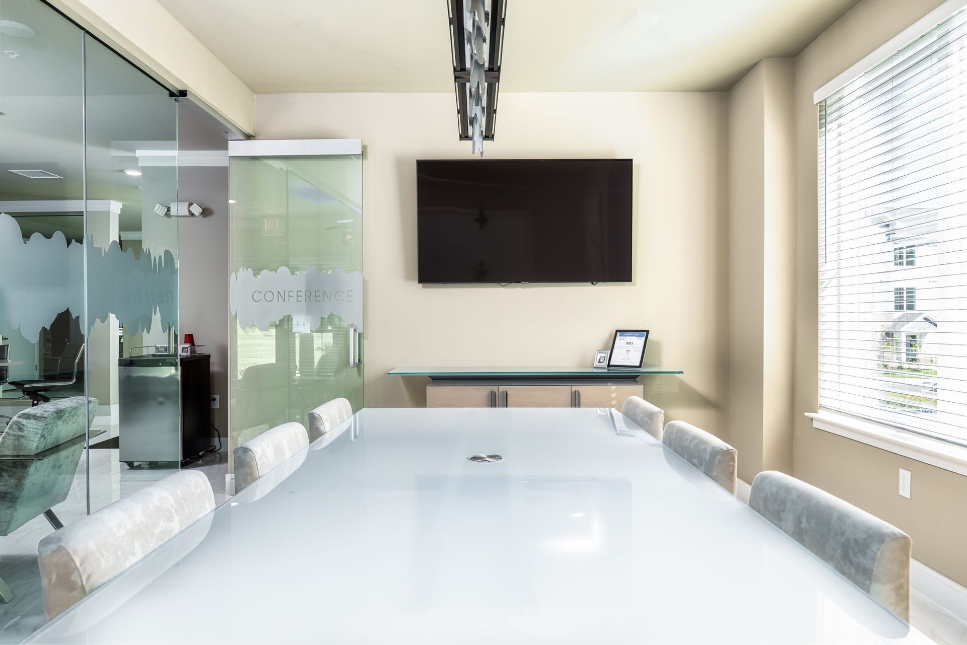 A conference room with a long table and chairs and a flat screen tv on the wall.