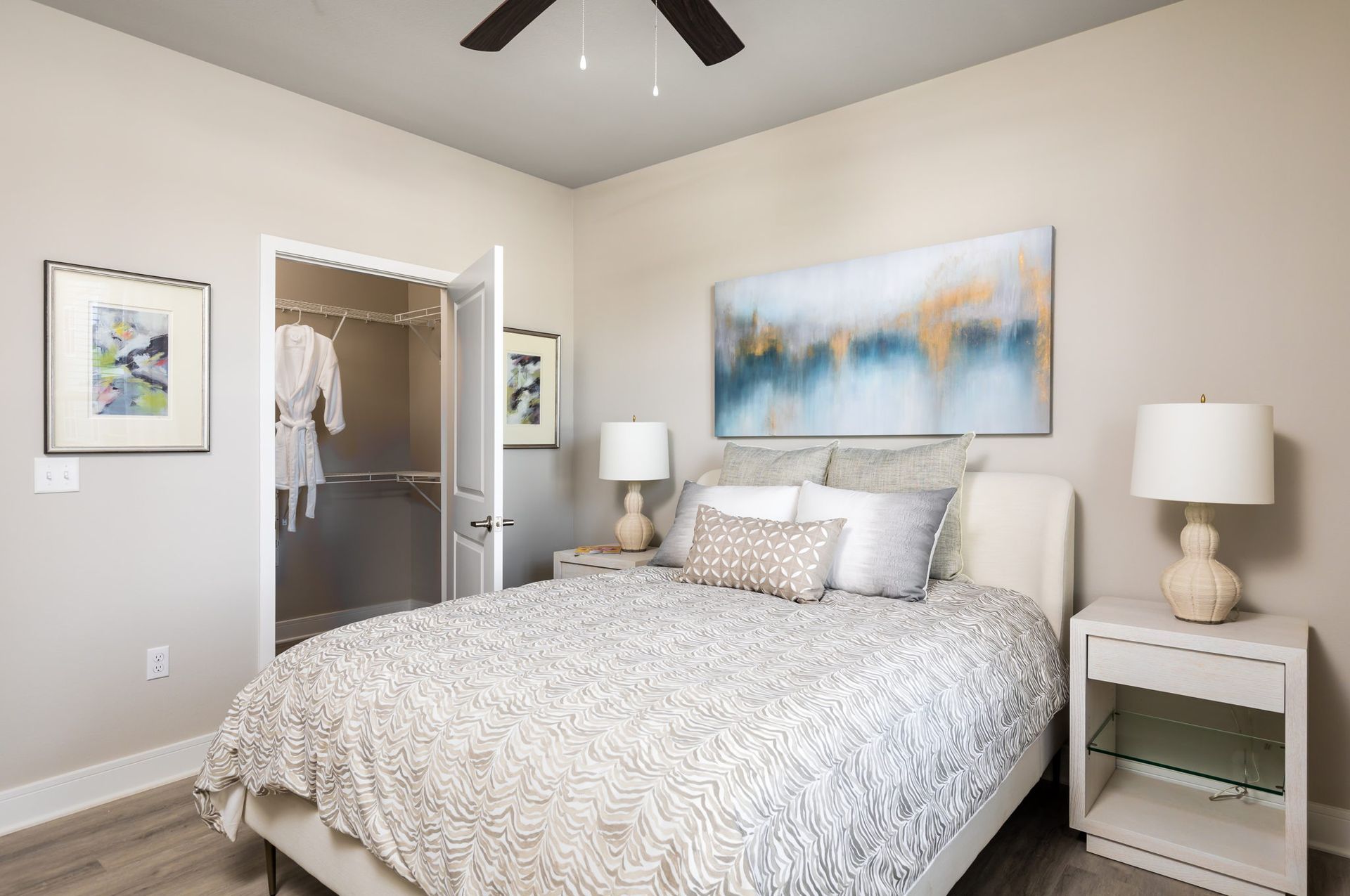 A bedroom with a bed , nightstands , lamps and a ceiling fan.