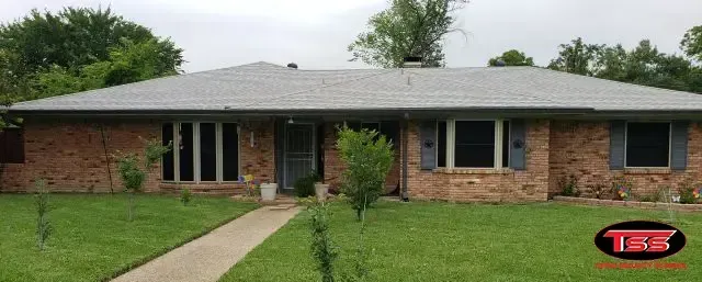 A brick house with a gray roof and shutters
