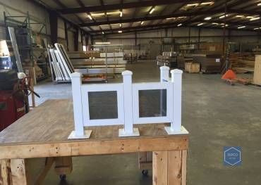 A white fence is sitting on top of a wooden table in a warehouse.