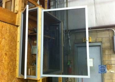 A window with a screen on it is open in a room.