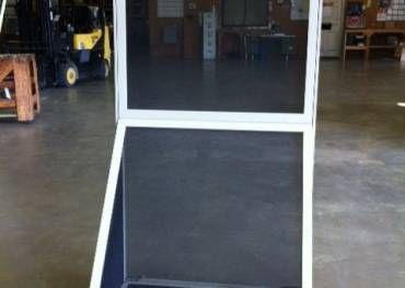 A screen door is sitting in a warehouse next to a forklift.