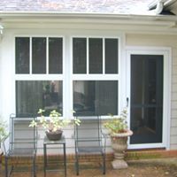A white house with a screened in porch and a sliding glass door.