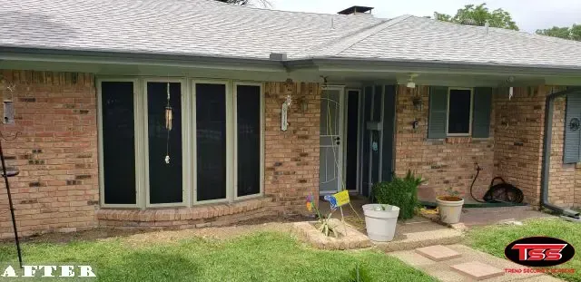 A brick house with black windows and a gray roof.