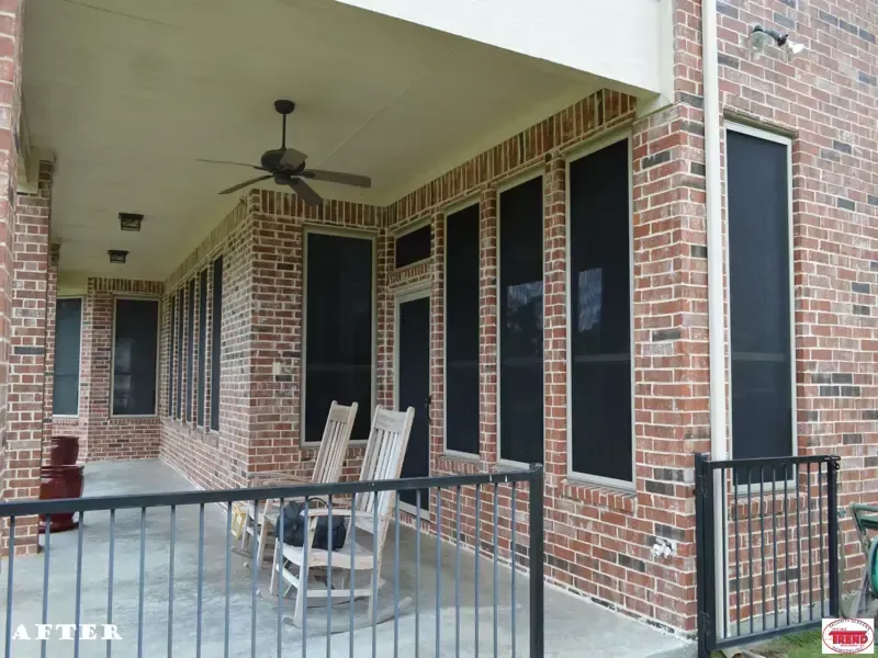 A screened in porch with rocking chairs and a ceiling fan