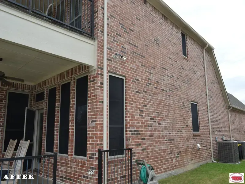 A brick house with black screens on the windows and a balcony.
