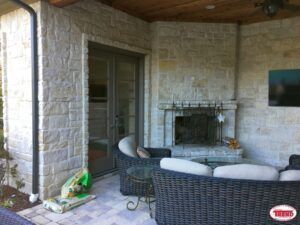 A patio with a fireplace , couch , chairs and a table.