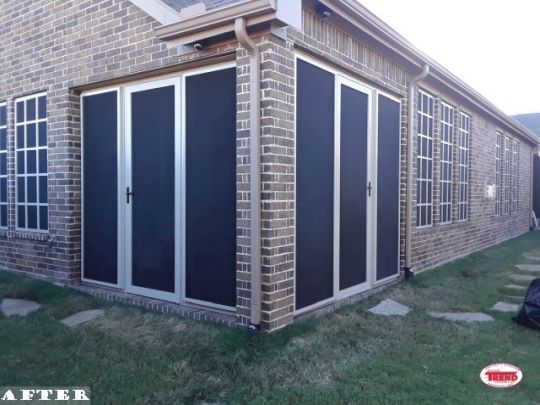 A picture of a brick house with black screen doors