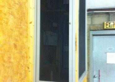 A door with a screen on it is in a room with a yellow wall.