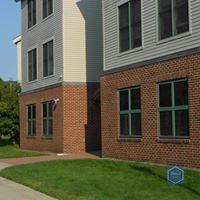 Two brick buildings with green windows are next to each other on a sunny day.