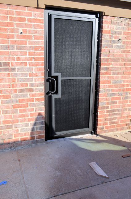 A brick building with a screen door in front of it