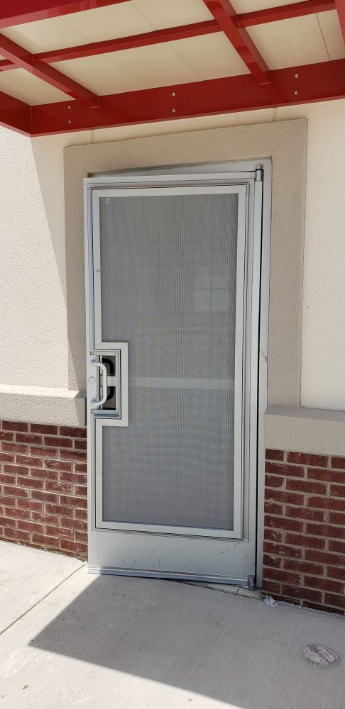 A door with a screen on it is on a brick wall