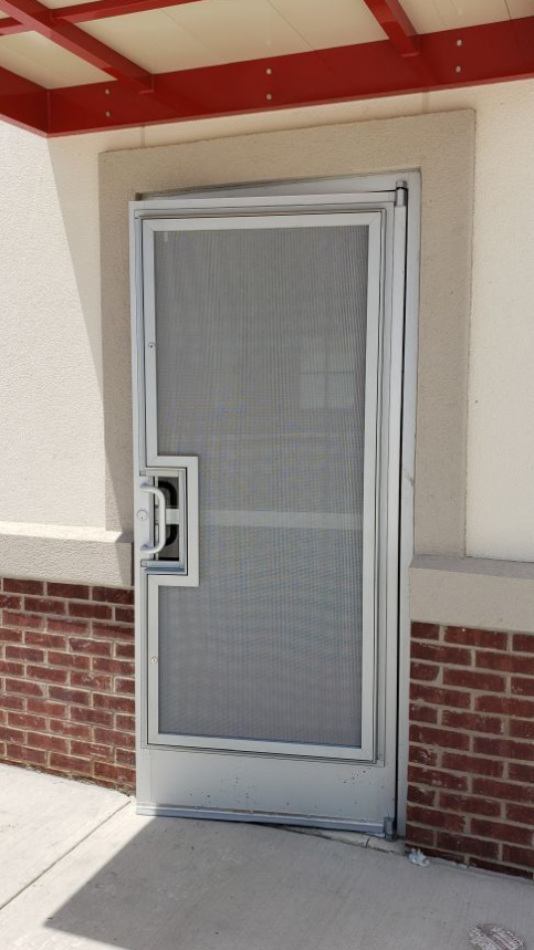 A door with a screen on it is on a brick wall