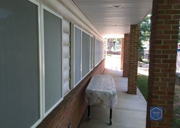 A long porch with a table on it and a brick wall.