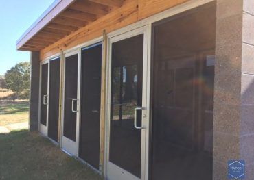 A row of screened in doors on the side of a building.