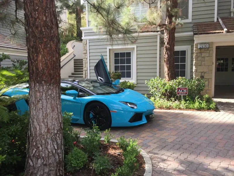 A blue sports car is parked in front of a house