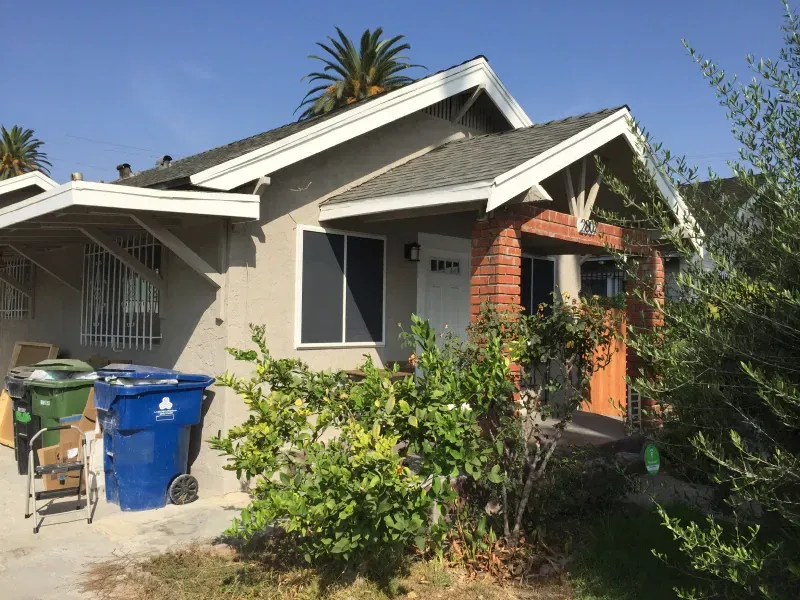 A house with a blue trash can in front of it