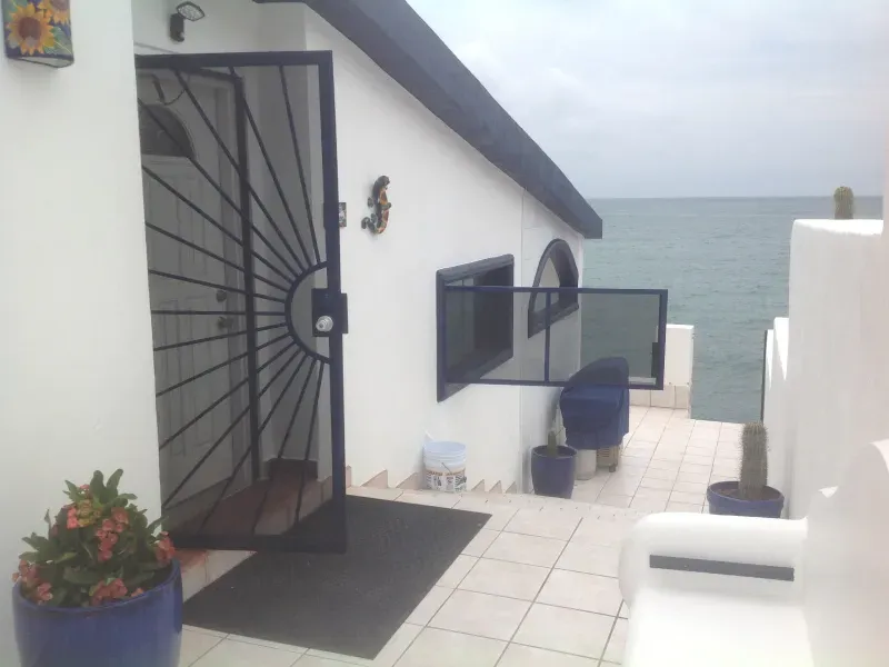 A white building with a black gate leading to the ocean