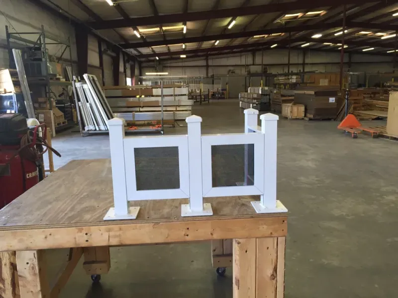 Two white fence posts are sitting on a wooden table in a warehouse.