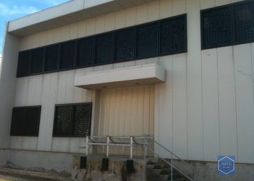 A large white building with black windows and stairs leading up to it.