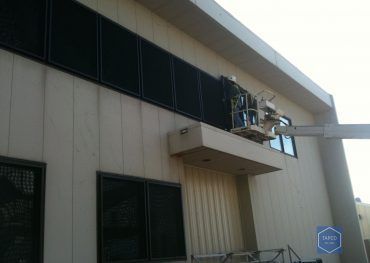 A man is painting a building with a crane.