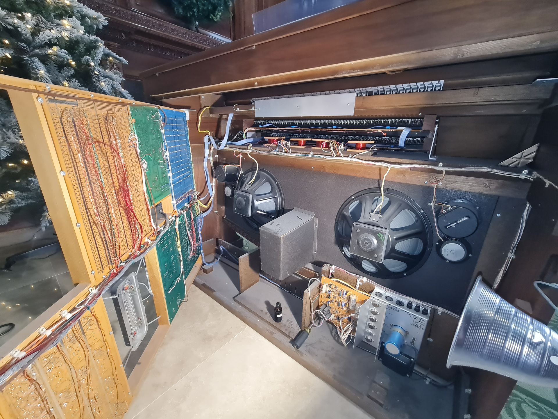 Inside of a vintage organ: wires, speakers, circuit boards.