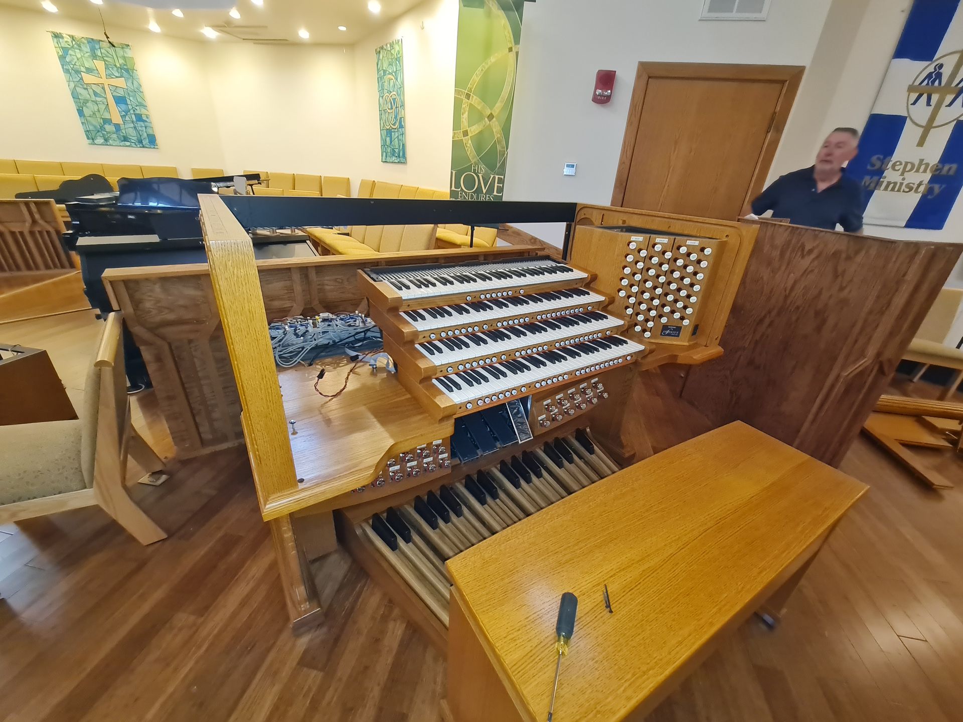 Wooden pipe organ, partially disassembled, in a church. A man observes.