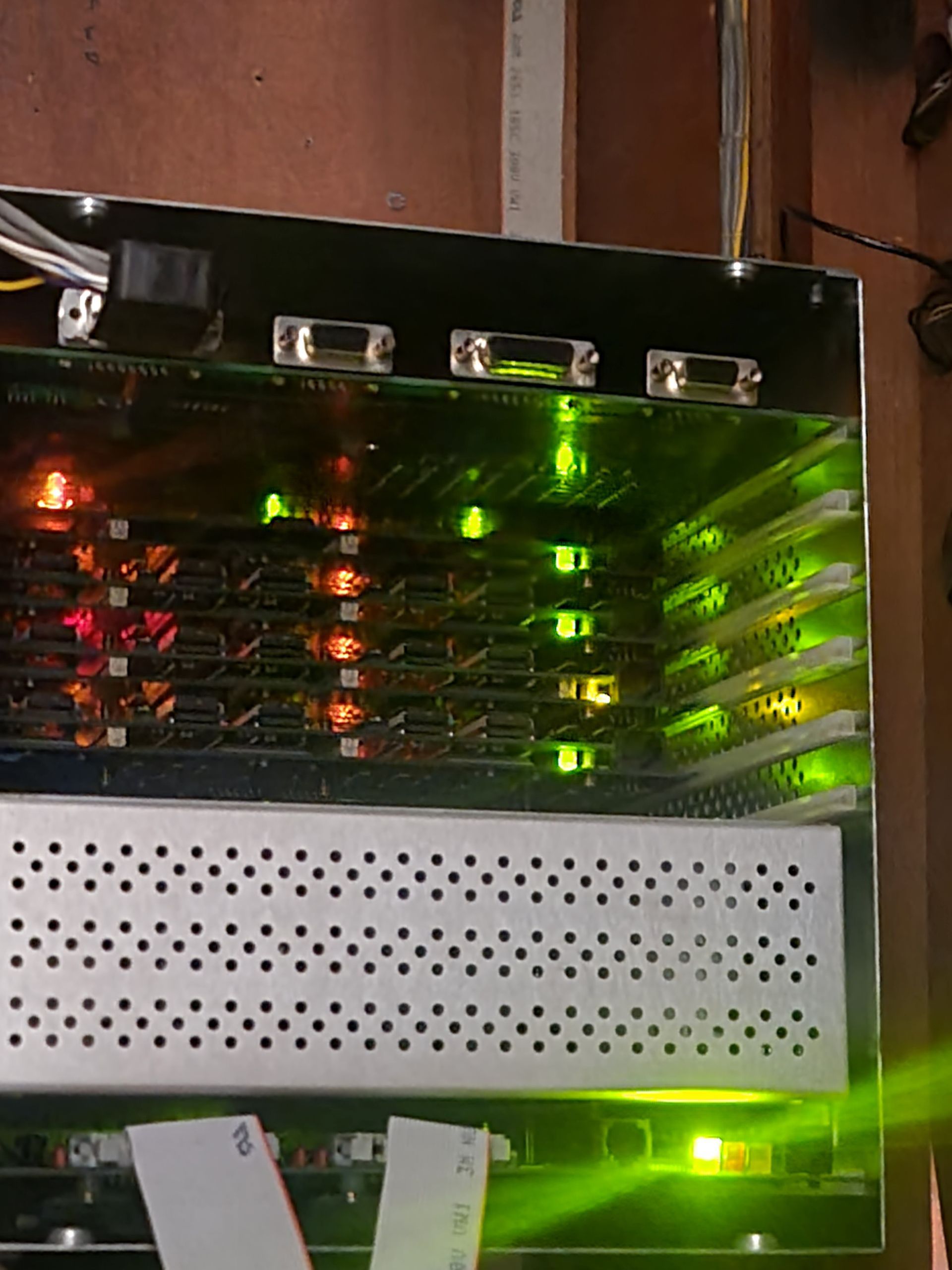 Server rack with multiple circuit boards lit by green and orange lights.