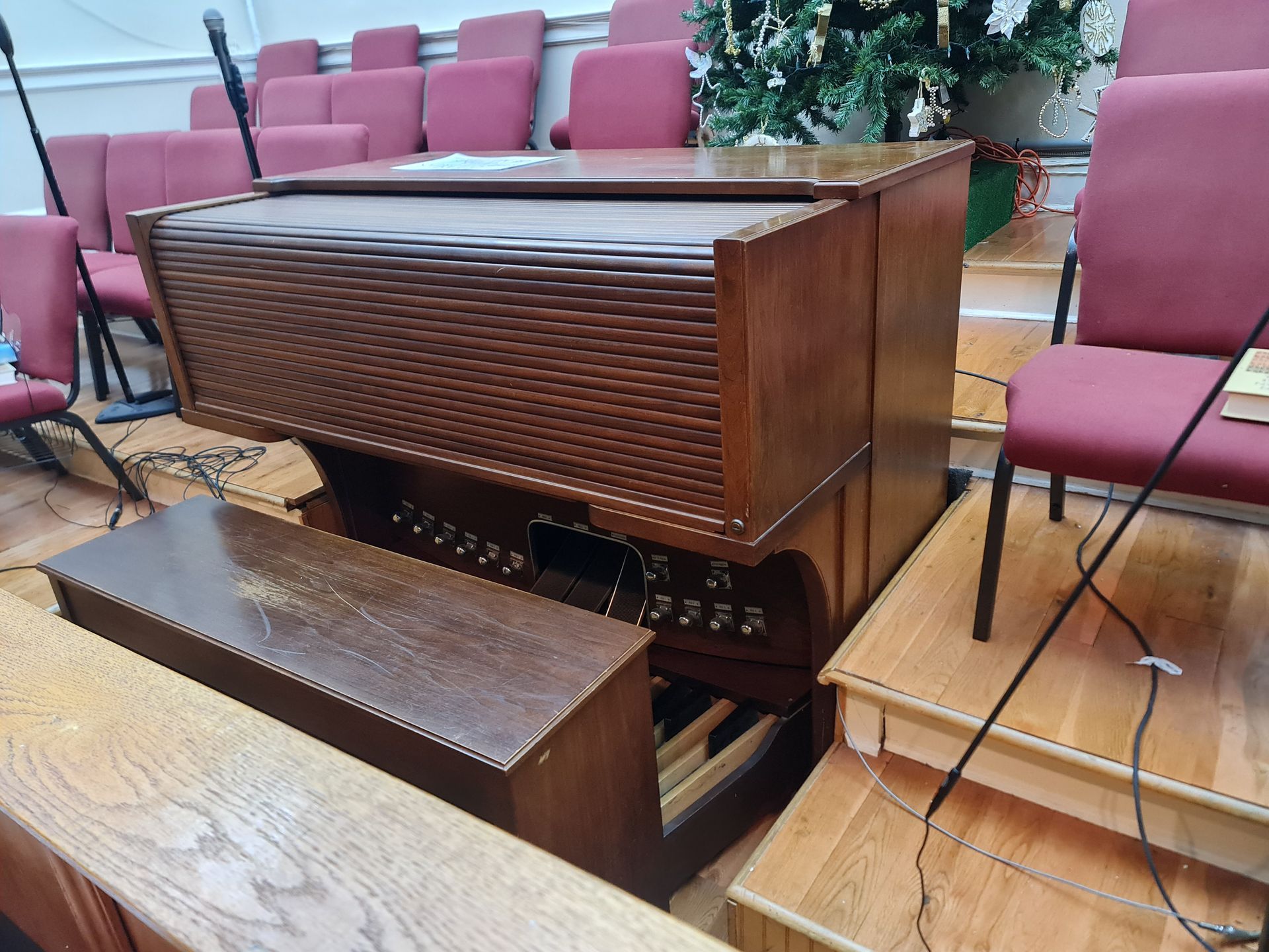 A black grand piano and stool sit in a bright room with a mountain view.