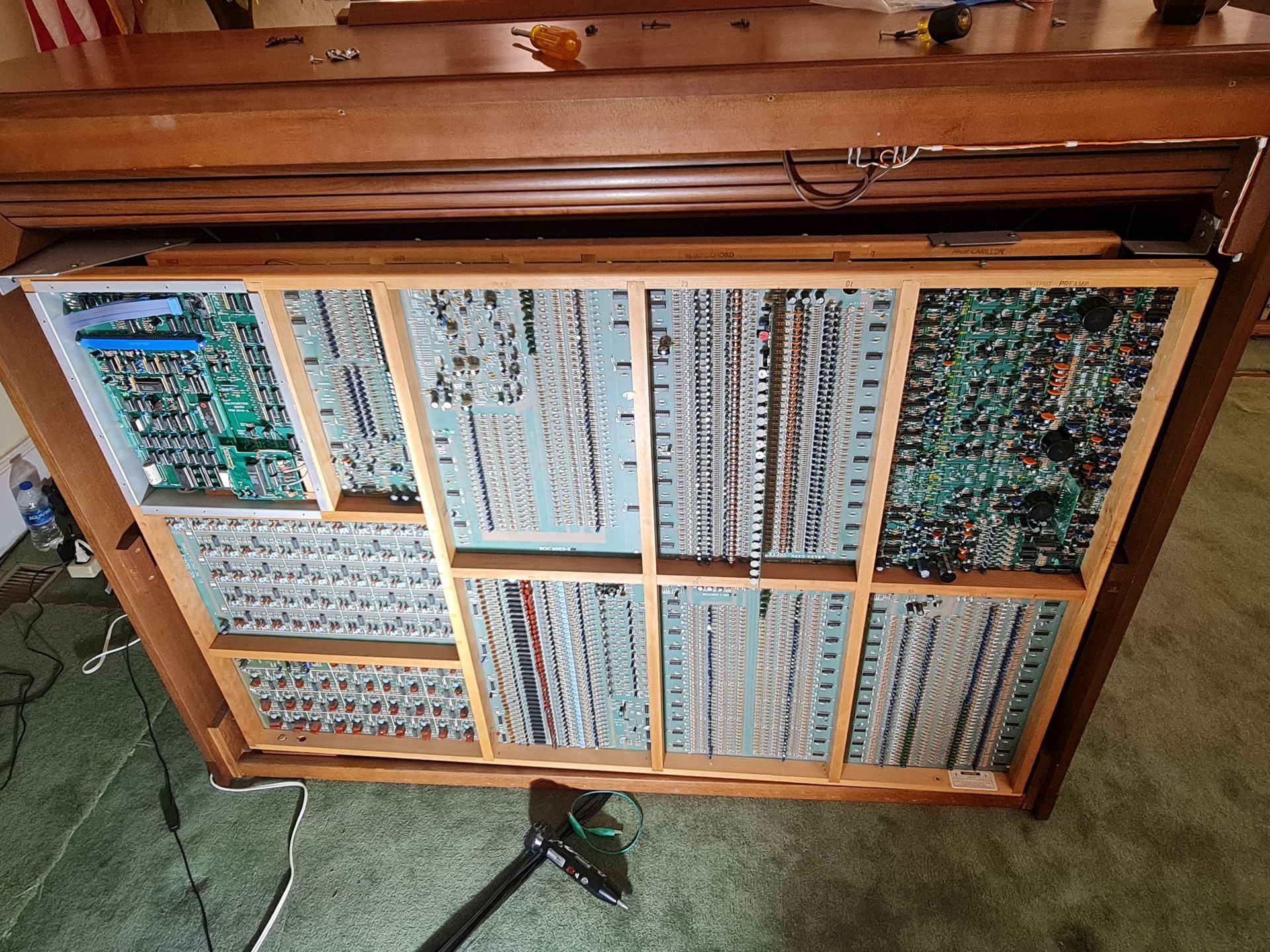 Wooden cabinet with many circuit boards inside; vacuum cleaner visible.