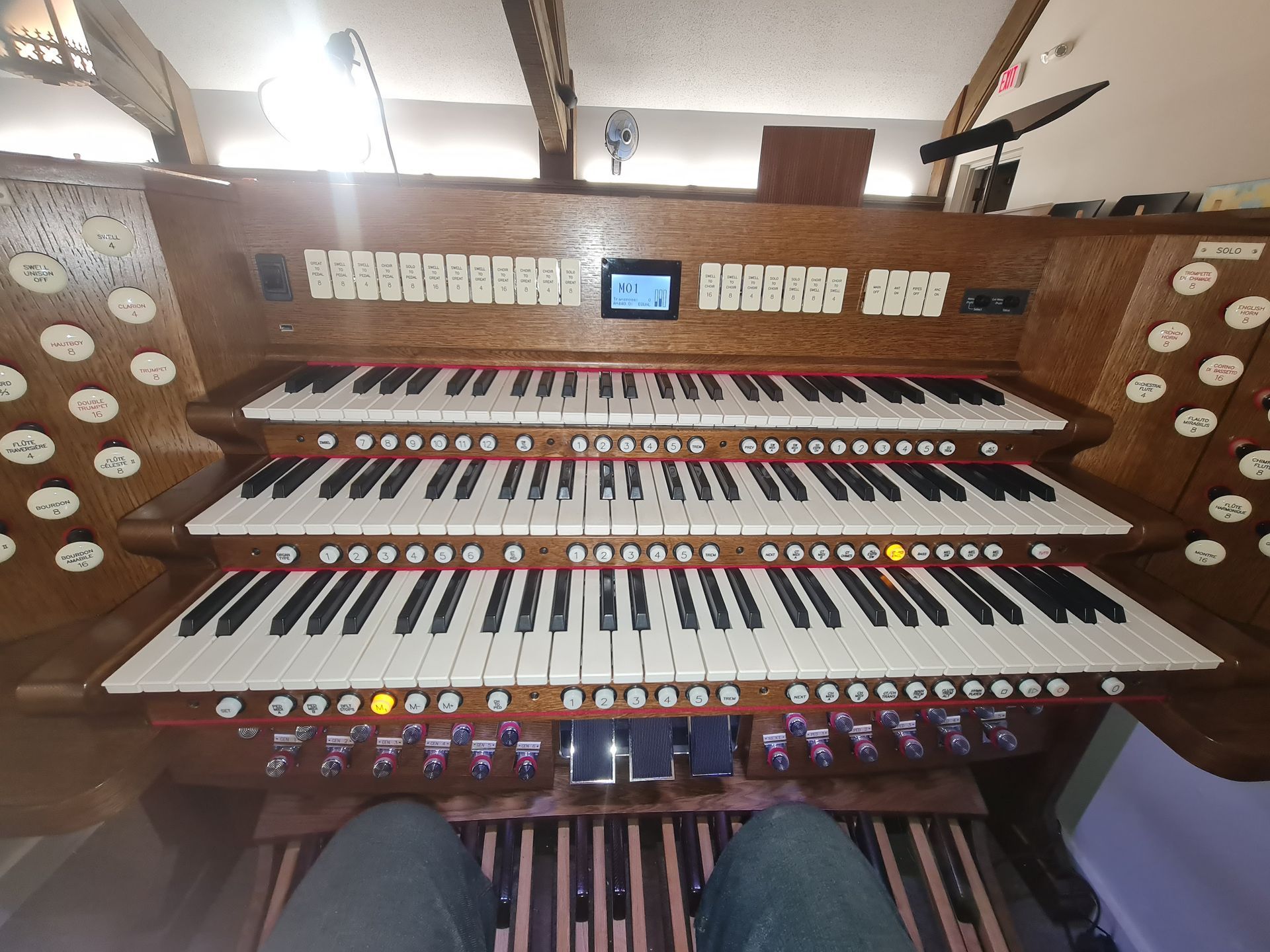 An organ with three keyboards, foot pedals, and many buttons. Seen from a seated position.