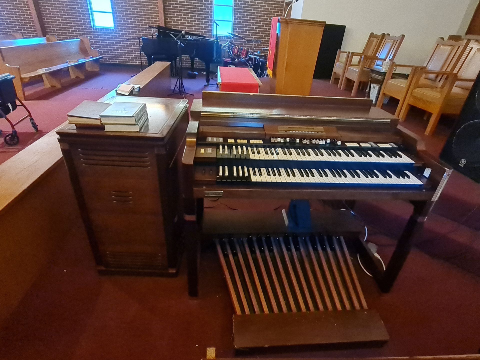 Hands adjusting the internal mechanism of a piano, keys visible.