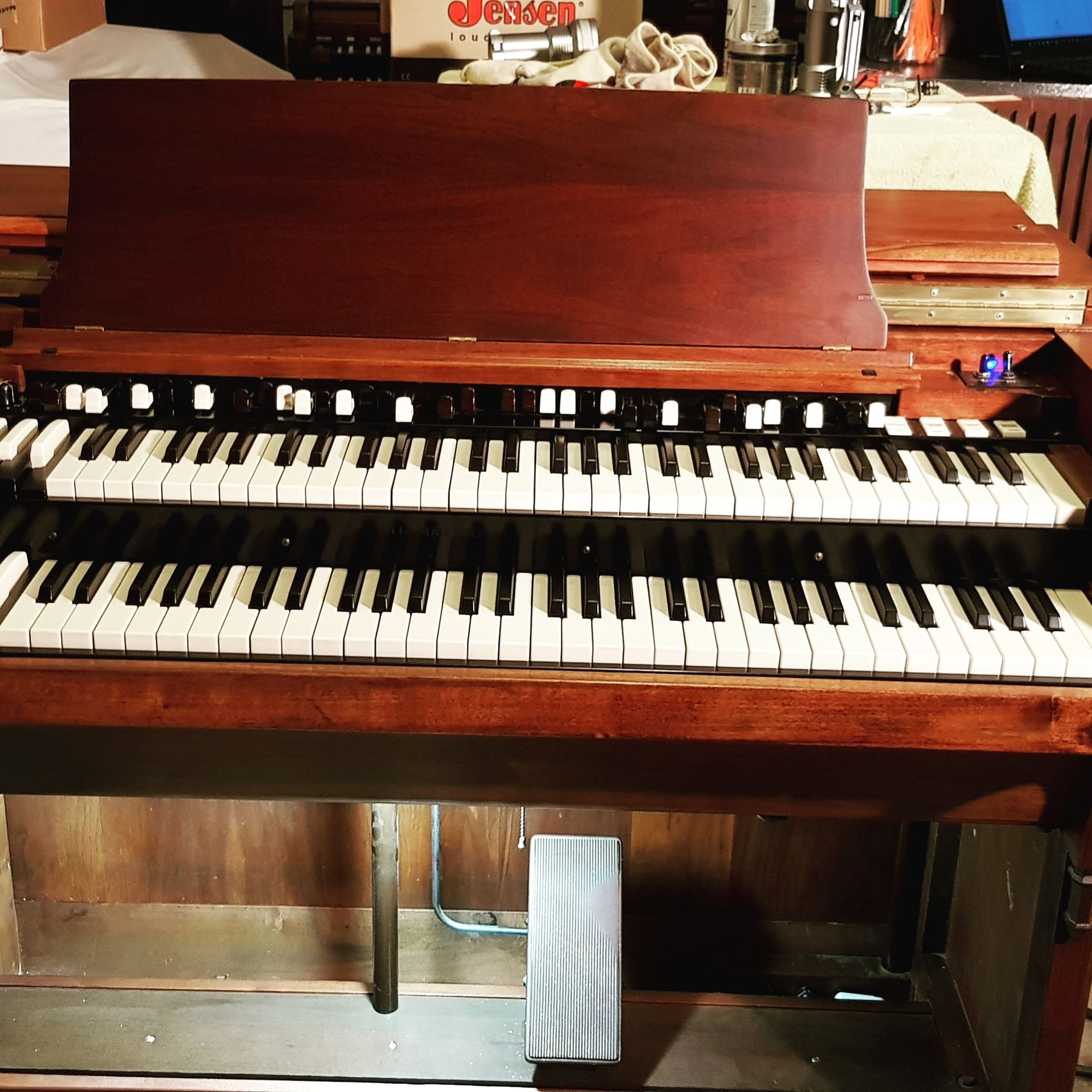 A vintage brown organ with two keyboards and foot pedals.
